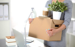 Happy team of businesspeople moving office, packing boxes, smiling.