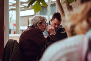 old man sitting down at a table eating